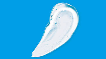 A smooth, translucent blob of a clear gel or lotion on a bright blue background.