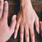A variety of hands with different skin tones are placed on a wooden surface, showcasing diversity and unity.