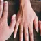 A variety of hands with different skin tones are placed on a wooden surface, showcasing diversity and unity.