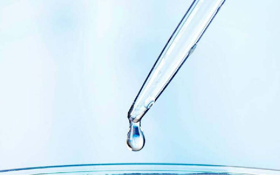 Goutte d'eau d'une pipette tombant dans un recipient transparent.