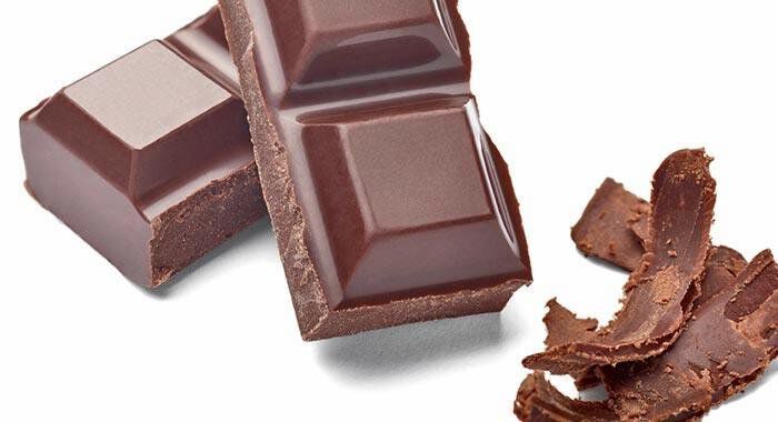 Alt text: Two pieces of dark chocolate with a pile of chocolate shavings beside them on a white background.