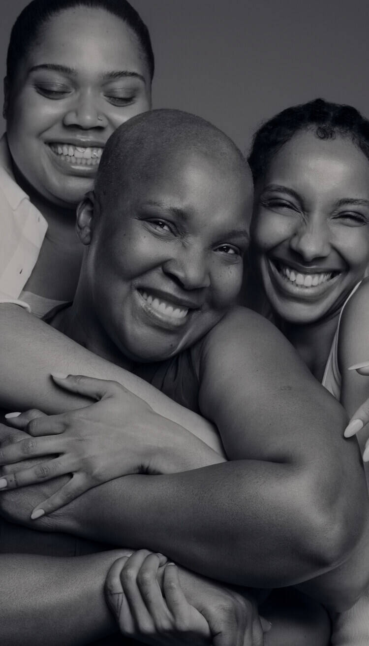 Trois femmes souriantes se sont enlacees, affichant de la joie et de la complicite.