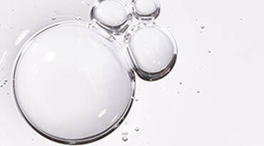 Close-up of transparent bubbles floating on a light background, with some larger and smaller bubbles clustered together.