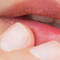 Close-up of a person's lips with a finger gently touching them.