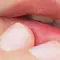 Close-up of a person's lips with a finger gently touching them.