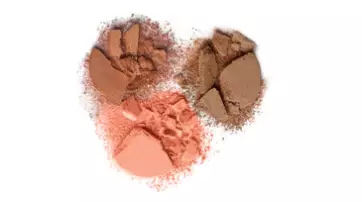 Three piles of loose powder in various shades of brown and peach, arranged in a heart shape against a white background.