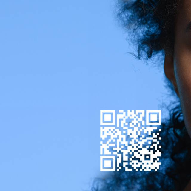 Une femme avec des cheveux frises regarde l'objectif, a cote d'un telephone affichant un visage numerique, avec un fond bleu et un code QR.