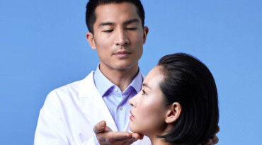 A medical professional gently examines a woman's face against a blue background.