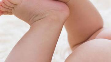 Close-up of a baby's feet and legs resting on a soft, fluffy surface.