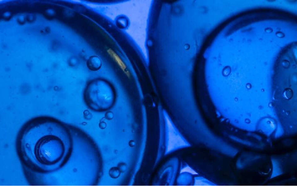 Des bulles et des spheres bleues flottent dans un fond bleu, creant un effet abstrait et lumineux.