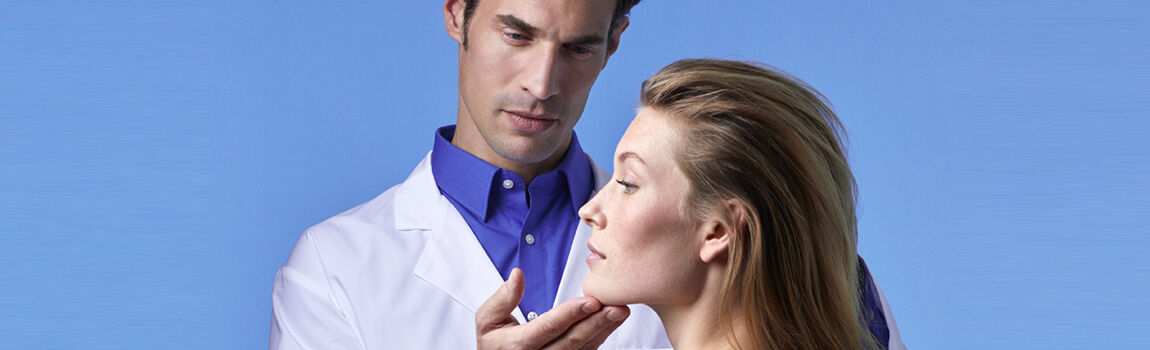 A healthcare professional examining a woman's jawline against a light blue background.