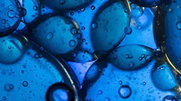 Close-up of various blue droplets with bubbles, creating a textured and abstract pattern.