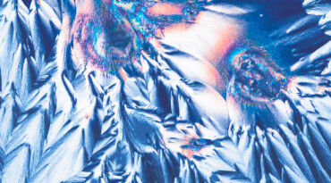 Abstract image featuring vibrant blue and orange crystalline structures, resembling pointed peaks and jagged textures against a dark background.