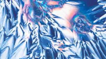 Abstract image featuring vibrant blue and orange crystalline structures, resembling pointed peaks and jagged textures against a dark background.