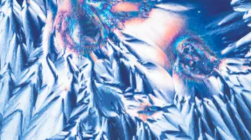 Abstract image featuring vibrant blue and orange crystalline structures, resembling pointed peaks and jagged textures against a dark background.