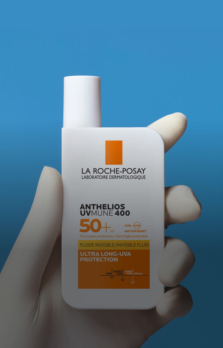 Flacon de protection solaire La Roche-Posay Anthelios UV Mune 400, affichant un indice de protection SPF 50+, tenu par une main en gant blanc.