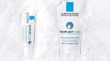 Two La Roche-Posay skincare products are displayed on a snowy background. One is a small tube labeled "Cicaplast Lips," and the other is a larger tube labeled "Cicaplast Hands."