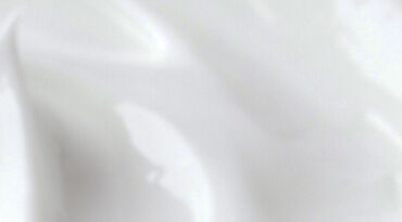 A smooth, shiny surface of white cream or lotion, with subtle waves and gradients.