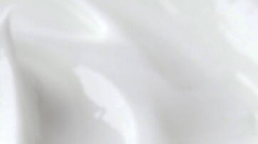 A smooth, shiny surface of white cream or lotion, with subtle waves and gradients.
