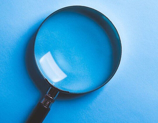 A large magnifying glass resting on a light blue surface.