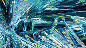 Abstract image featuring vibrant, colorful crystal formations with sharp, elongated structures and dynamic patterns, resembling a burst of light and color.