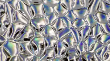 Close-up of an abstract surface featuring shiny, iridescent patterns with a variety of light reflections and colors.