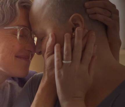 Deux personnes souriantes s'enlacent tendrement en se touchant le front, partageant un moment de complicite et d'affection.