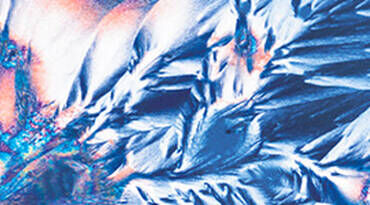 Abstract image featuring intricate patterns and textures in vibrant shades of blue, white, and hints of orange, resembling crystalline formations.