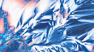 Abstract image featuring intricate patterns and textures in vibrant shades of blue, white, and hints of orange, resembling crystalline formations.