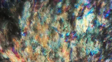 Close-up image of a textured surface featuring vibrant colors, including shades of blue, green, and orange, with a shimmering, iridescent effect.