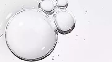 Close-up of clear bubbles of varying sizes, with light reflecting off their surfaces against a plain white background.