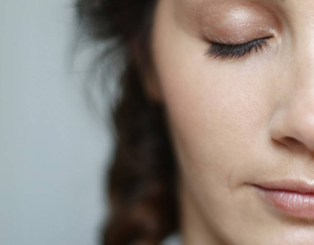 Une femme avec les yeux fermes et un visage detendu, mettant en avant ses cils et un maquillage subtil.