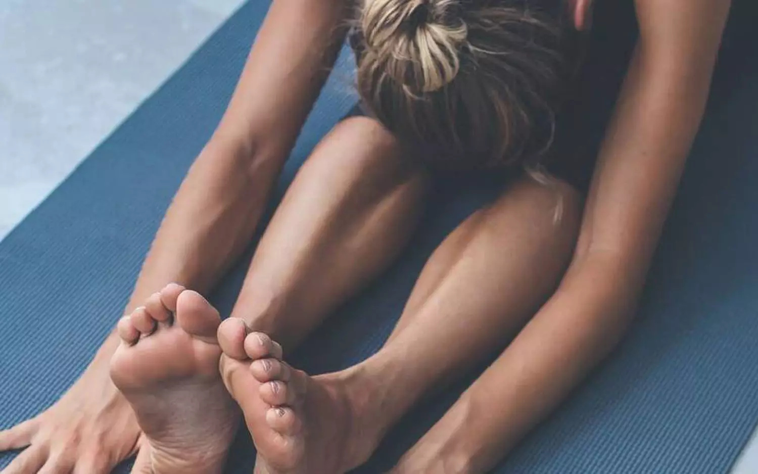 Une personne faisant des etirements assis sur un tapis de yoga.