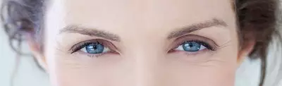 Close-up of a woman's face focusing on her expressive blue eyes, framed by natural brows and soft skin.