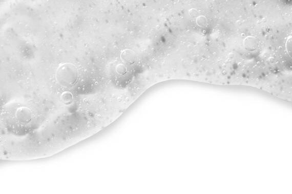 Texture de liquide mousseux et cremeux avec des bulles sur un fond blanc.