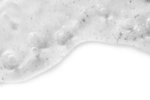 Texture de liquide mousseux et cremeux avec des bulles sur un fond blanc.