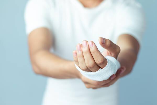 Un homme portant un bandage sur la main, tendant la main vers l'avant.