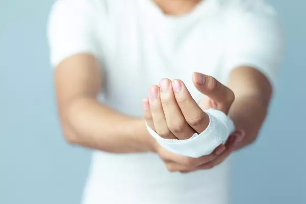 Un homme portant un bandage sur la main, tendant la main vers l'avant.