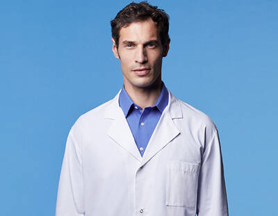 Un homme en blouse blanche regarde l'objectif avec un fond bleu clair.