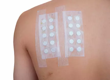 Bandages adhesifs sur le dos, contenant plusieurs pastilles blanches, numerotes 1 et 2.