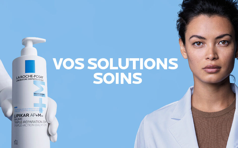 Une femme en blouse blanche a cote d'une main tenant un flacon de Lipikar AP+M de La Roche-Posay, avec le texte « VOS SOLUTIONS SOINS » sur fond bleu.