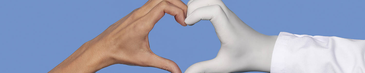 Une main nue et une main portant un gant medical blanc formant ensemble un coeur sur un fond bleu.