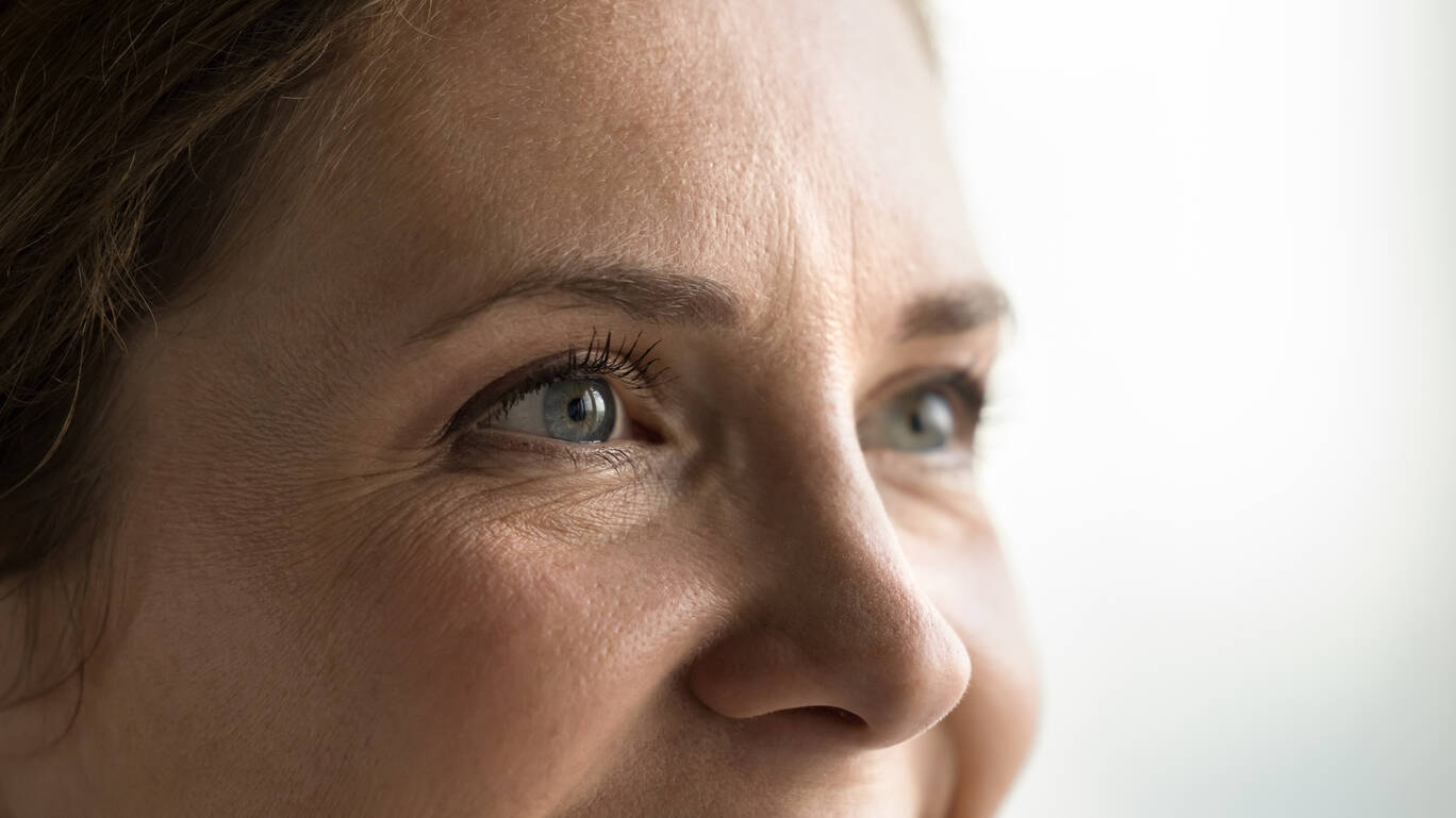 Gros plan sur le regard d'une femme mature, mettant en evidence les ridules et la texture naturelle de la peau.
