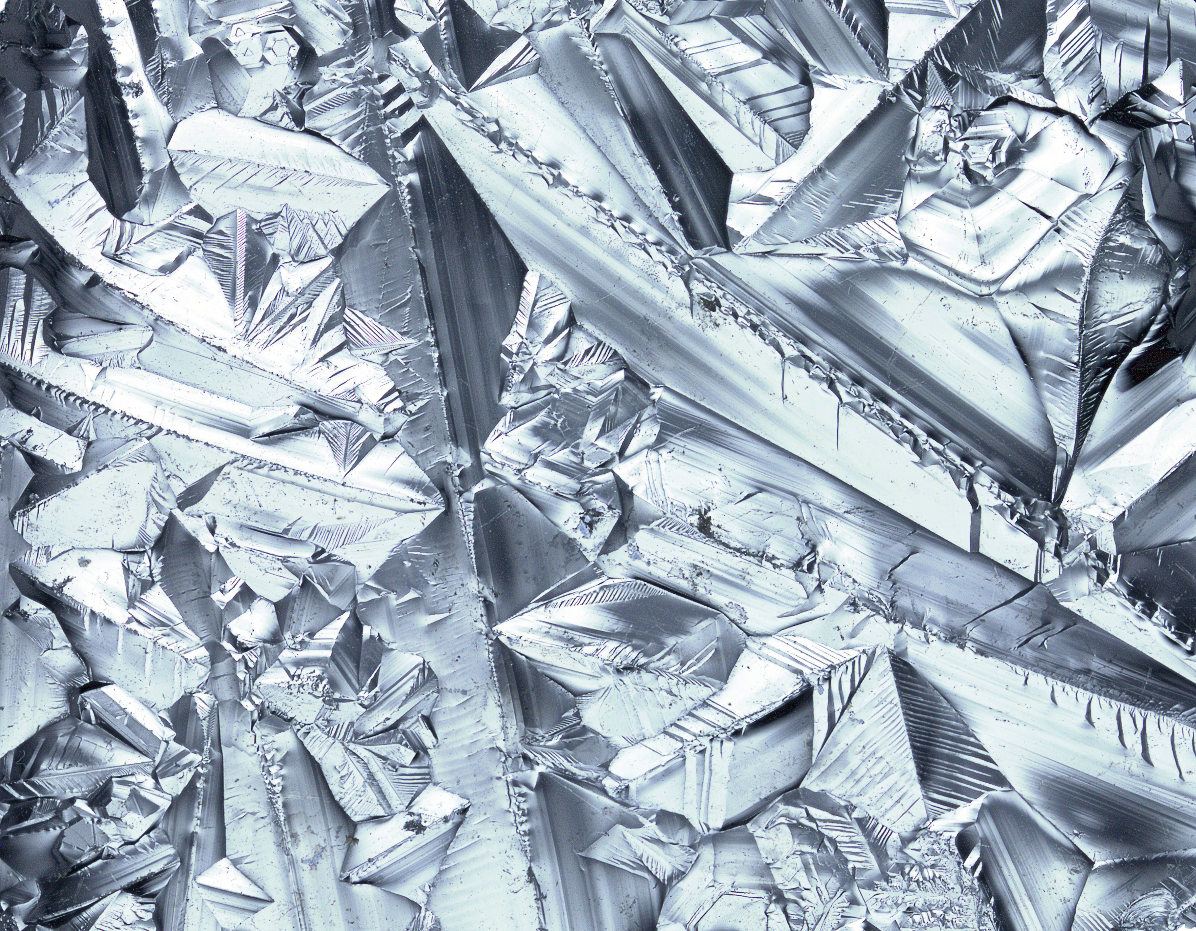 Texture de cristaux metalliques brillants, presentant des formes geometriques complexes et des reflets lumineux.