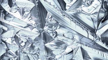 Texture de cristaux metalliques brillants, presentant des formes geometriques complexes et des reflets lumineux.