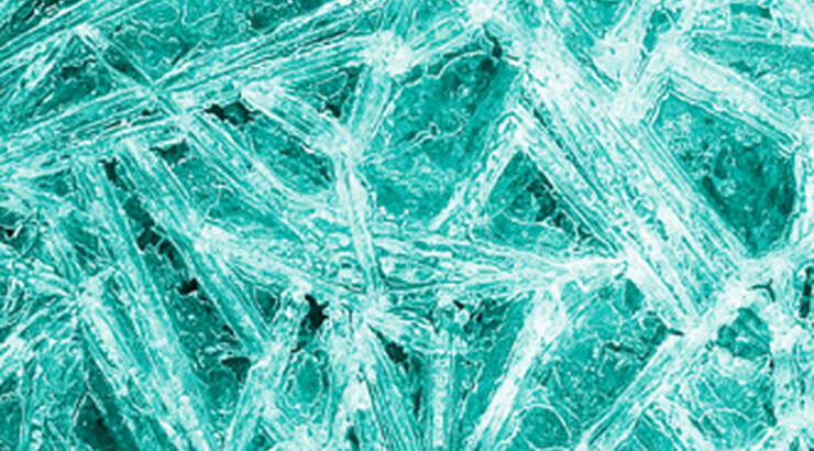 Close-up of textured ice with intricate, crystalline patterns and a turquoise hue.