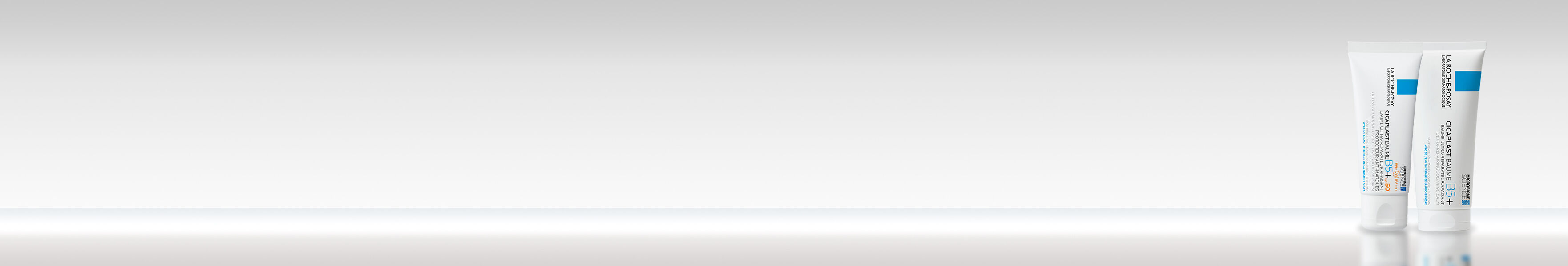 Deux tubes de creme sur un fond gris clair, avec une surface reflechissante.