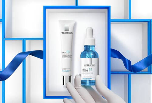 Image montrant deux produits de soin de la peau presentes dans un cadre bleu avec une bande. Un tube et un flacon sont elegamment disposes, evoquant une presentation raffinee.