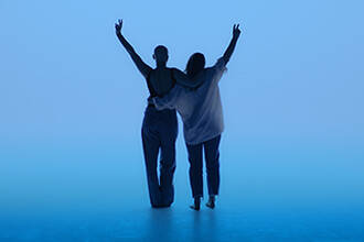 Silhouette de deux personnes s'enlacant, bras leves faisant le signe V de la victoire sur un fond bleu eclatant.