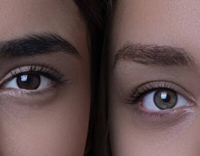 Deux yeux humains, l'un brun et l'autre bleu-vert, montrant des details des cils et des iris.